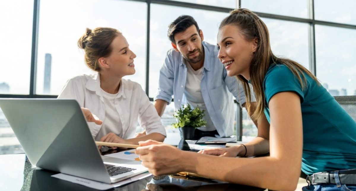 Three colleagues reviewing a draft together at a laptop