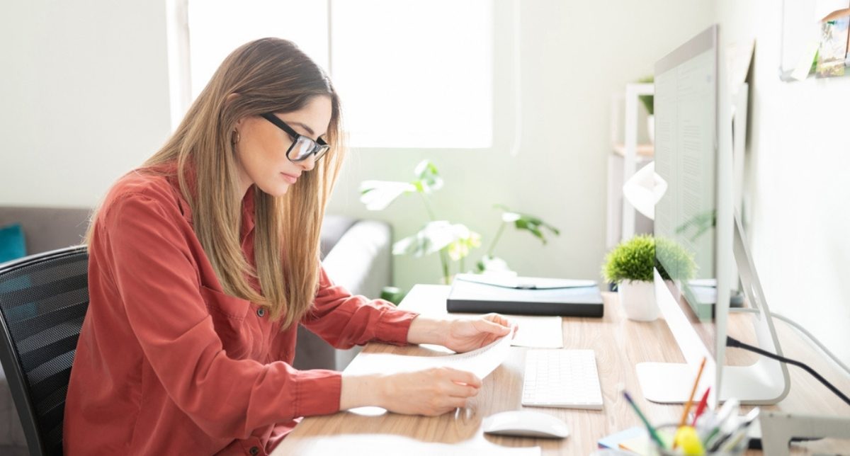 A specialist reviewing written notes at her desk A specialist reviewing written notes at her desk